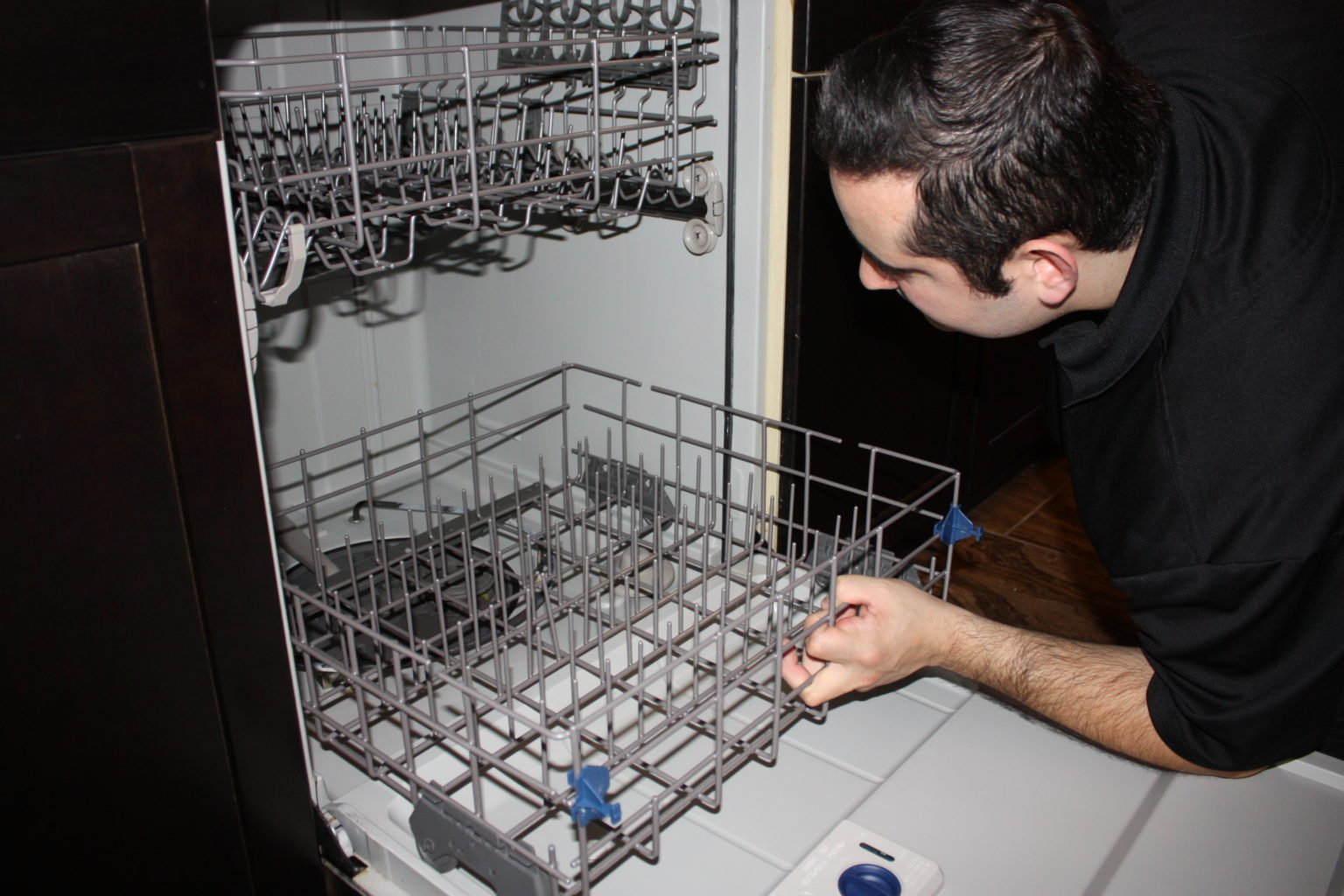 Technician inspecting the inside of a dishwasher during appliance repair